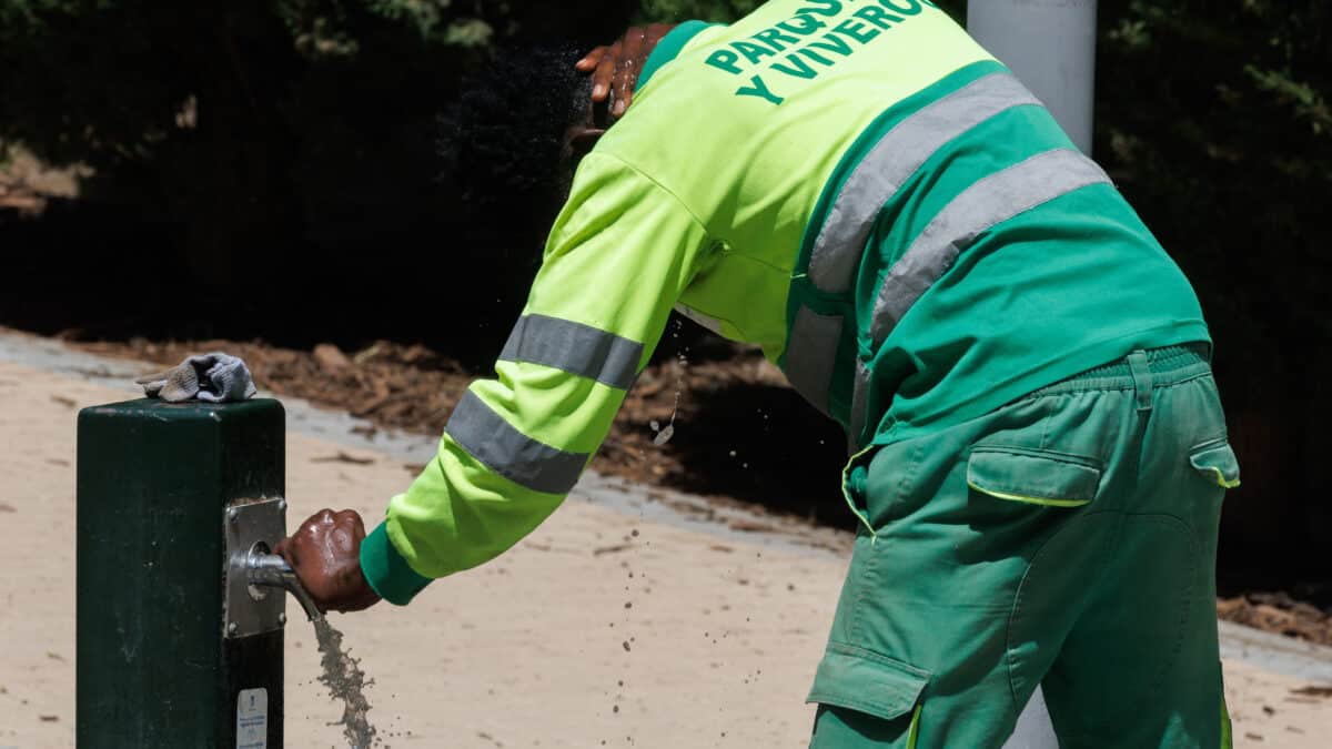 Un trabajador coge agua en una fuente en el Parque del Manzanares, en Madrid.