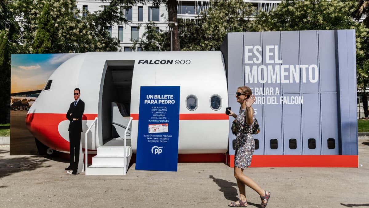 Una persona camina frente a la maqueta del avión Falcon 900 junto a la Plaza de Colón, Madrid