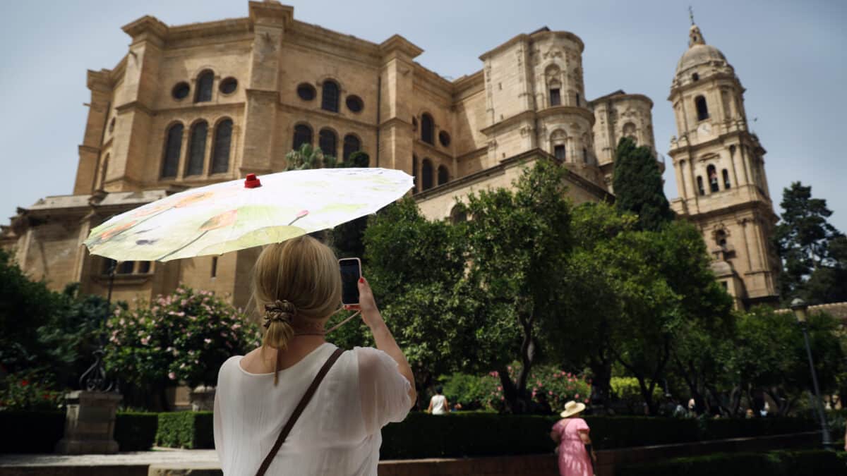 Una señora con un paraguas fotografía la Catedral de Málaga