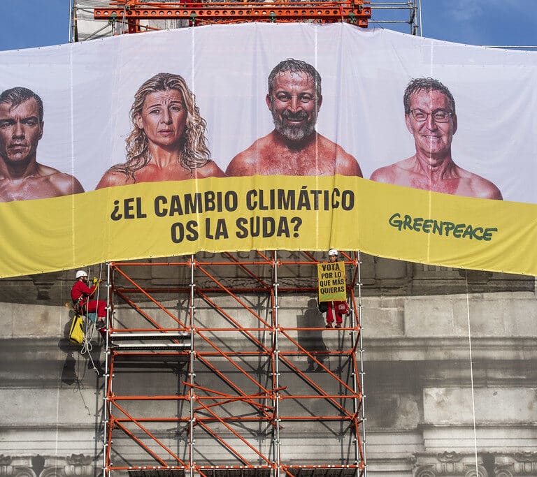 Greenpeace despliega una pancarta en la Puerta de Alcalá contra los principales candidatos: "¿El cambio climático os la suda?"