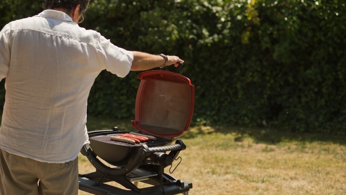 Hombre junto a una barbacoa de gas portátil