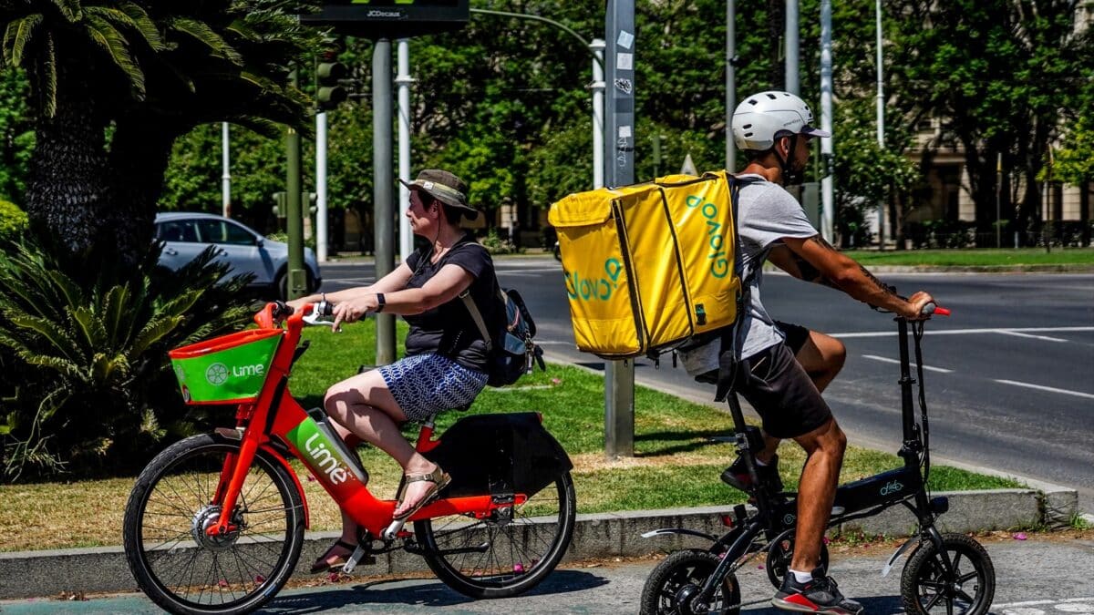 Una ciclista se cruza con un repartidor de Glovo en Sevilla.