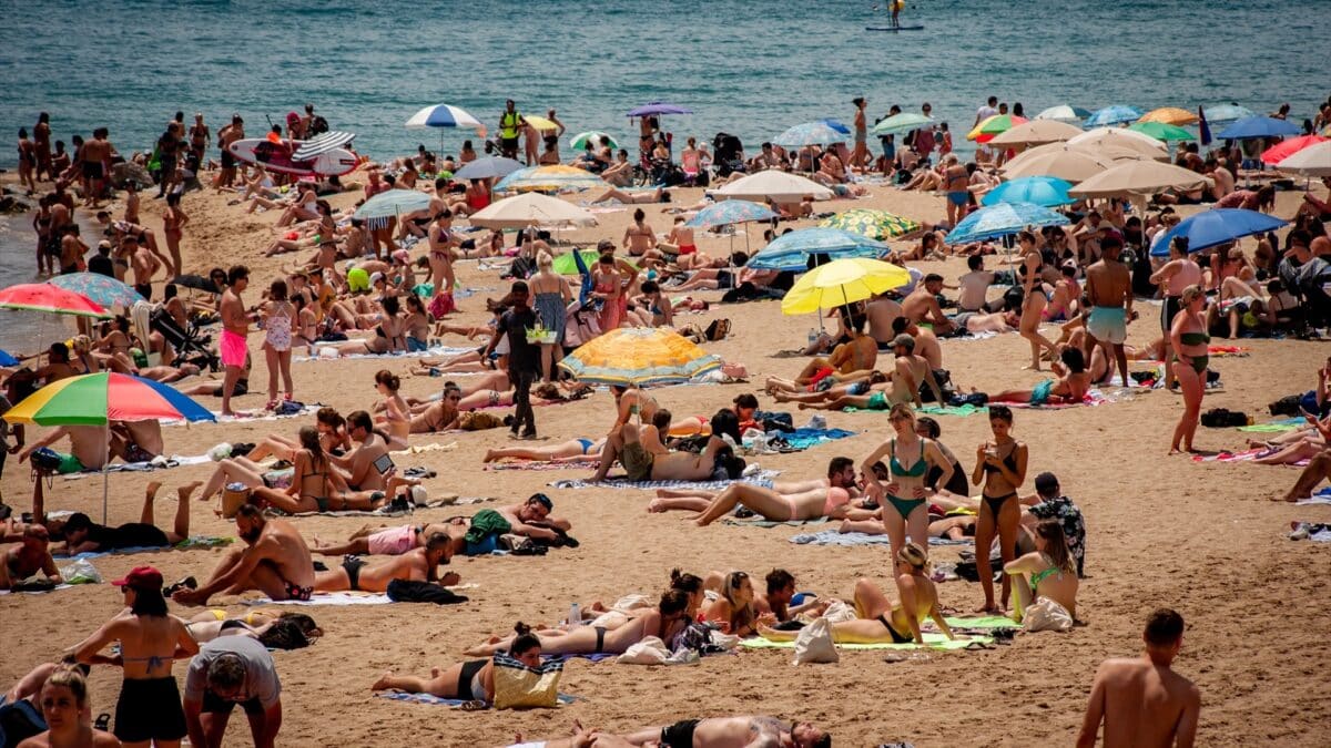Turistas y locales descansan tranquilos en una playa de Barcelona.