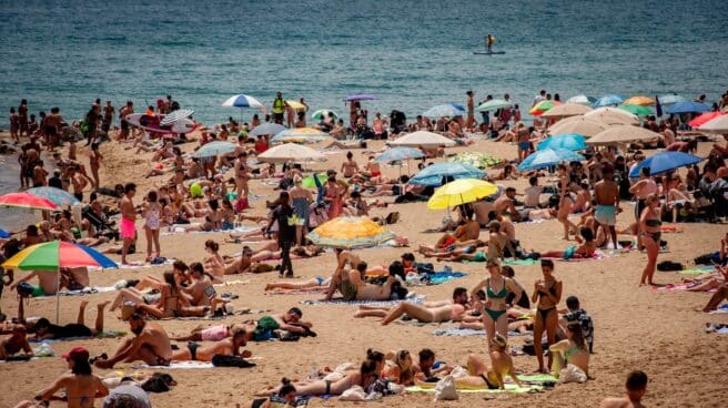 Turistas y locales descansan tranquilos en una playa de Barcelona.