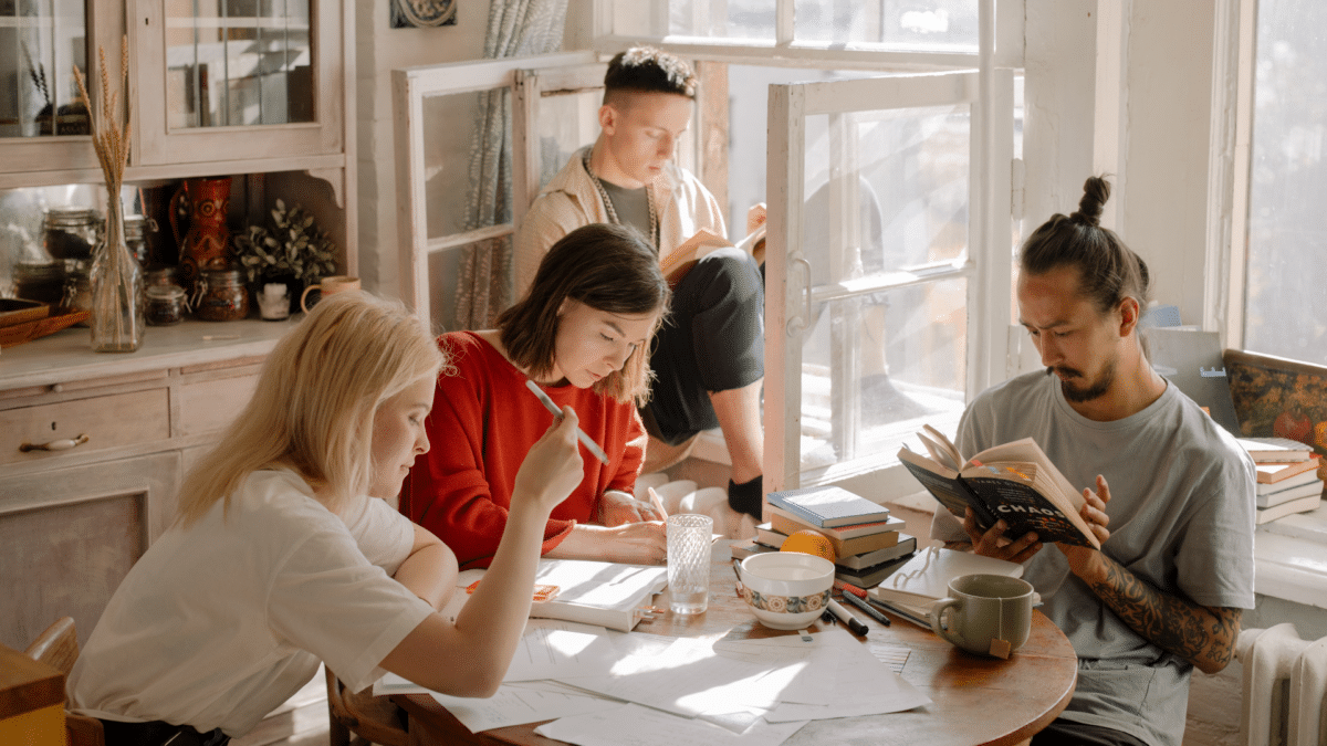 Varios universitarios estudiando en un piso compartido, sabiendo qué ayudas ofrece la Comunidad de Madrid para el alquiler de viviendas