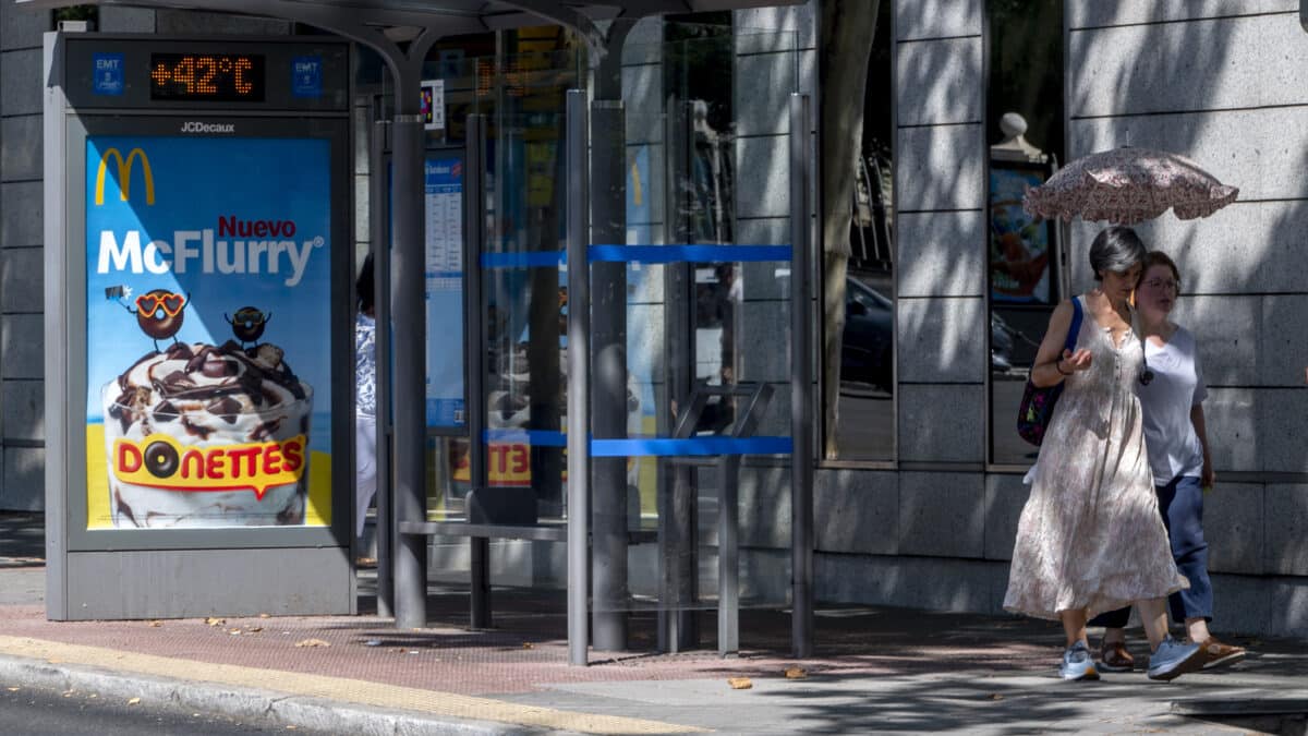 Dos personas caminan con paraguas en una calle de Madrid en plena ola de calor, la cuarta que se registra en lo que va de verano.