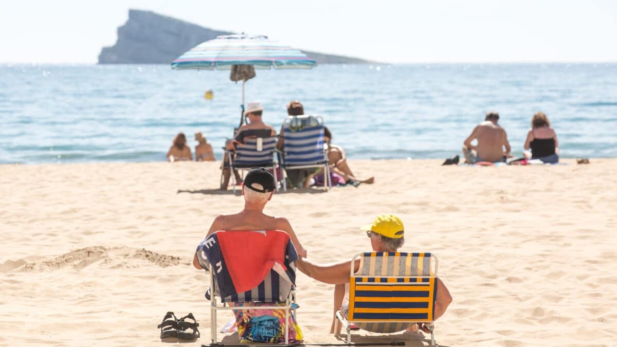 Una pareja de ancianos toma el sol en una playa de Benidorm.