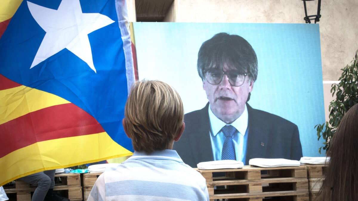 Un niño observa la intervención telemática de Puigdemont en el mitin central del partido JxCAT