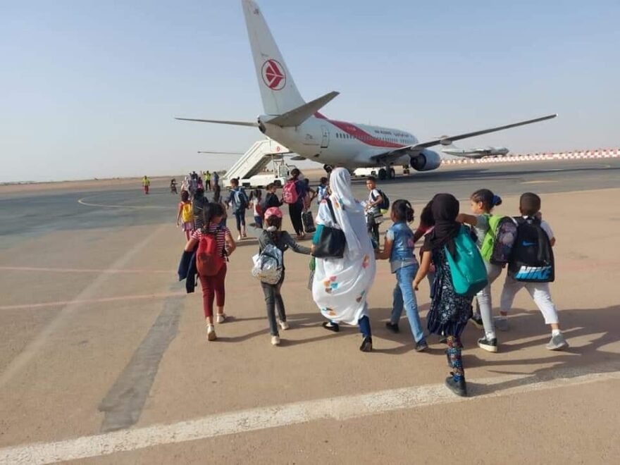 Niños y niñas saharauis de Vacaciones en Paz camino al avión en el aeropuerto de Tinduf (Argelia). 