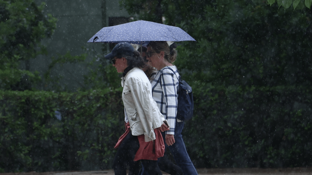 Varias personas pasean con el paraguas, tras las lluvias torrenciales que acompañan la llegada del otoño meteorológico 2023