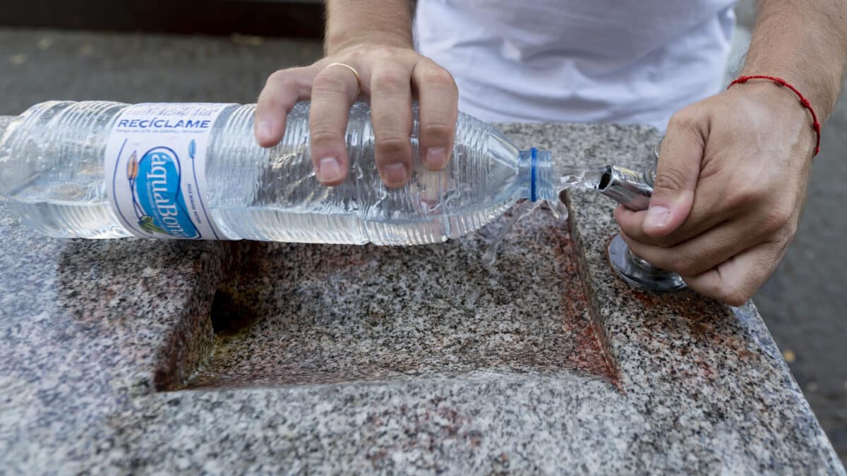 Una persona llena una botella de agua de una fuente, a 21 de agosto de 2023, en Madrid (España).