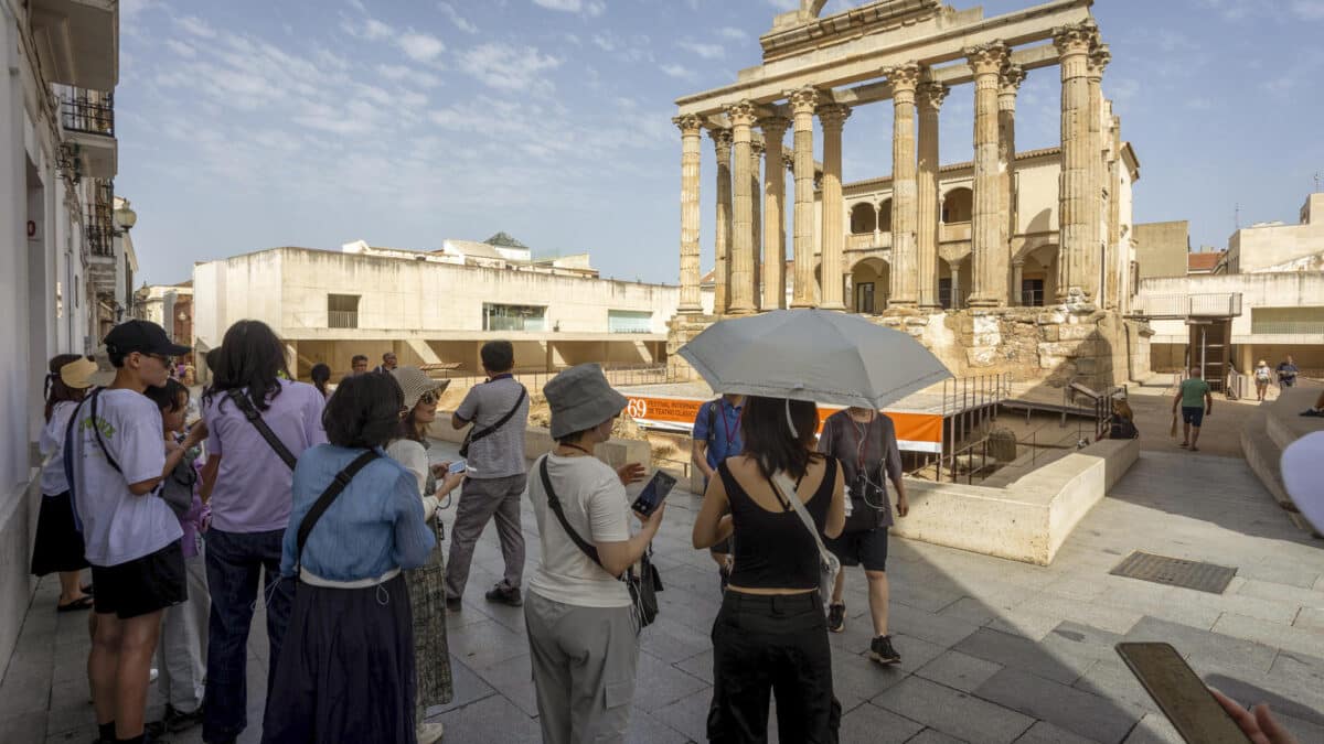 Unos turistas se protegen del sol con un paraguas en Mérida.