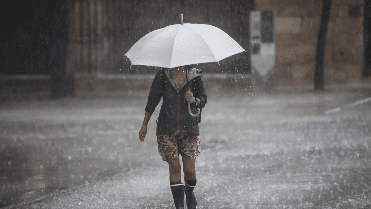 Una persona camina con un paraguas bajo la lluvia, sabiendo cuándo empieza el otoño astronómico de 2023