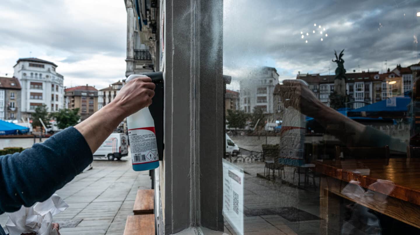 Una camarera limpia el cristal de su cafetería en Vitoria, Álava, País Vasco