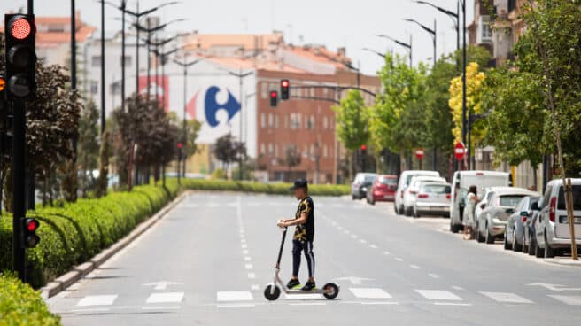 A young man crosses the road on an electric scooter under the sun on Kalle Hellin on July 11, 2023.
