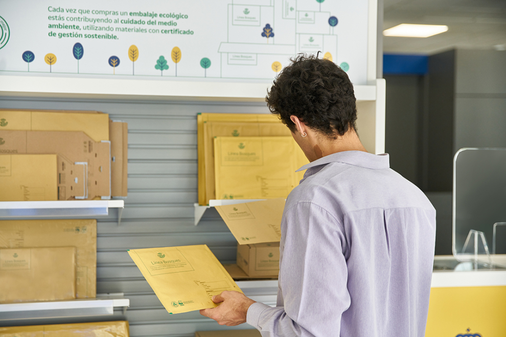 Hombre joven usando paquetes sostenibles y ecológicos en una oficina de Correos