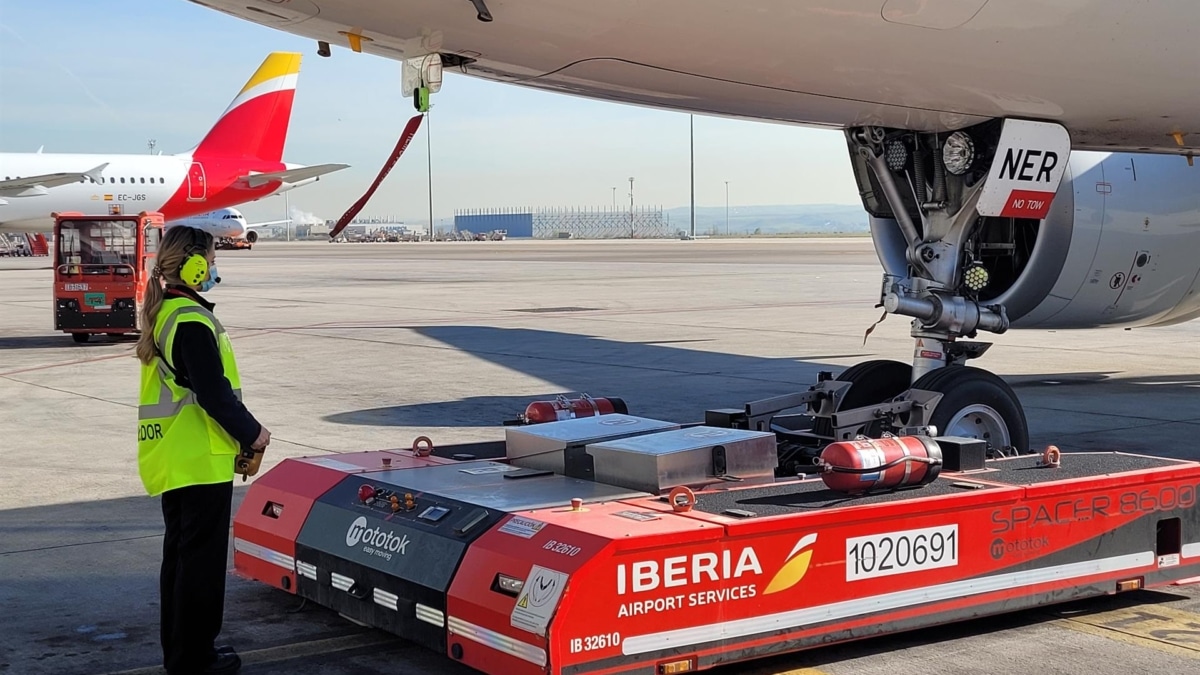 Una empleada de Iberia Airport Services al pie de un avión.