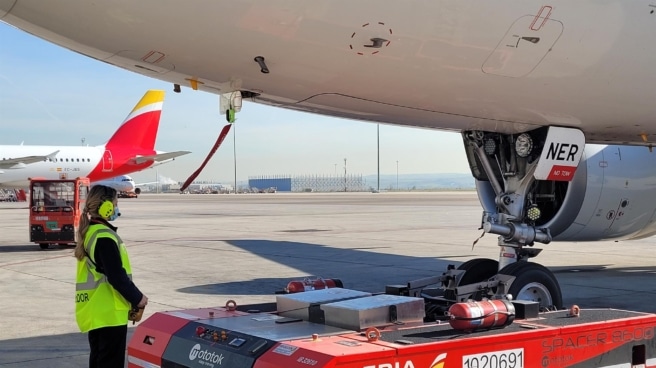 Una empleada de Iberia Airport Services al pie de un avión. Una empleada de Iberia Airport Services al pie de un avión.