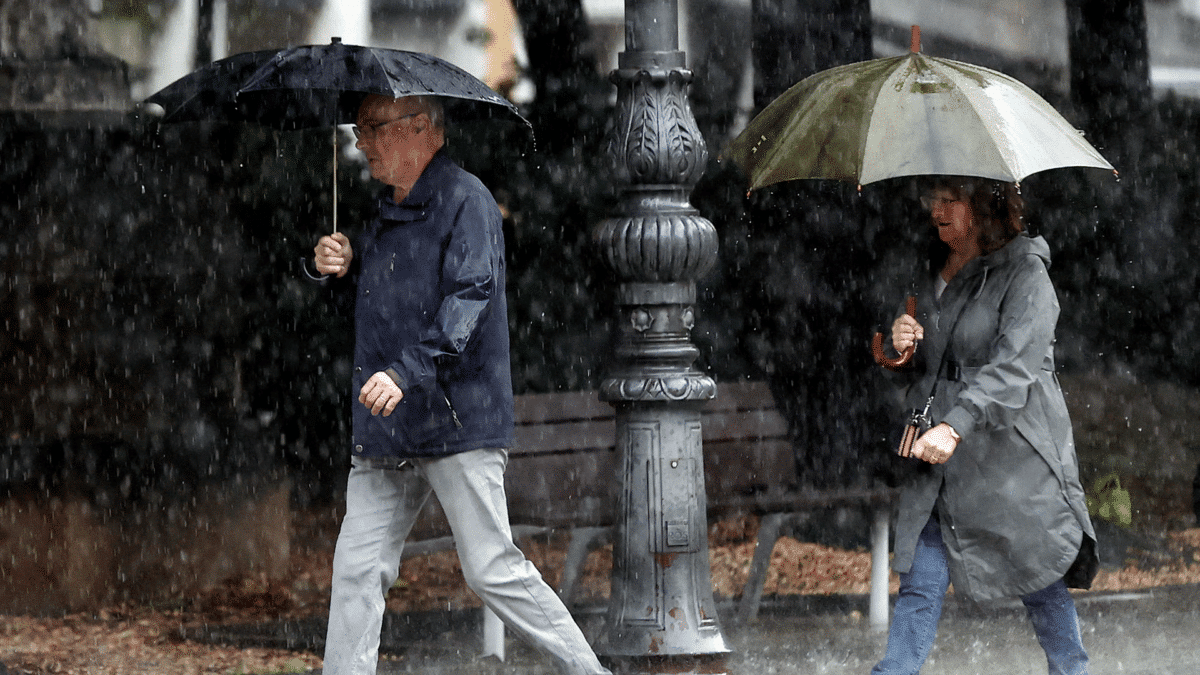 Dos personas se protegen de la lluvia con sus paraguas mientras Jorge Rey vuelve a contradecir las previsiones de la Aemet para este otoño 2023