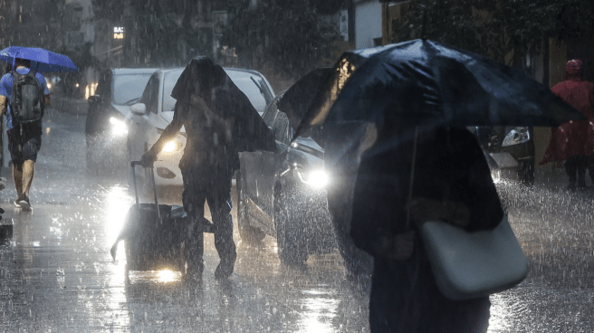 Llega una nueva DANA a España Varias personas con paraguas bajo la lluvia con la llegada de una nueva DANA a España que traerá chubascos y tormentas intensas