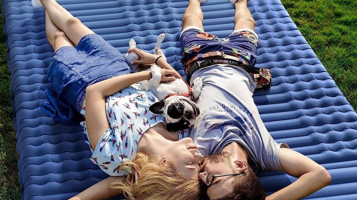 Hombre, perro y mujer tumbados sobre un colchón hinchable