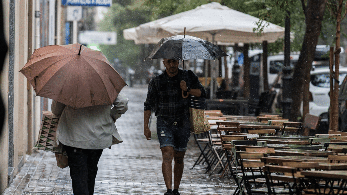 Varias personas se resguardan de la lluvia con paraguas, sabiendo qué tiempo hará el fin de semana en España tras el paso del ex huracán Franklin