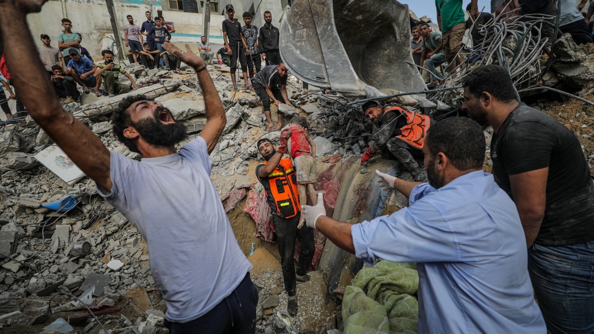 Unos palestinos recuperan el cadáver de una niña en un campo de refugiados en Gaza.