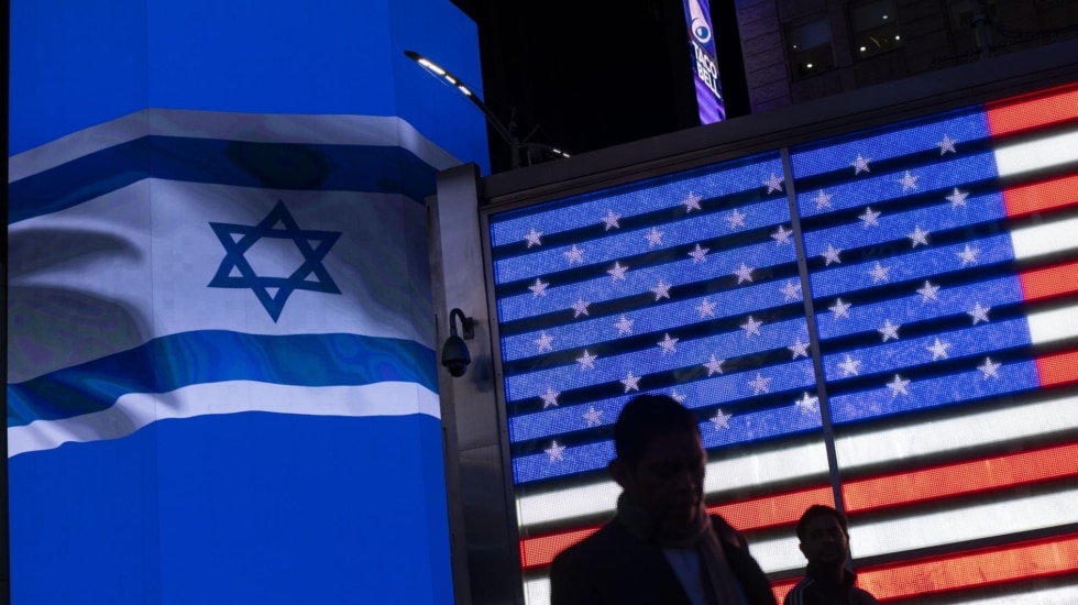 Un grupo de personas pasa junto a una valla publicitaria con una bandera israelí desplegada con motivo de una concentración de apoyo a Israel en Times Square, Nueva York, Estados Unidos, 19 de octubre de 2023