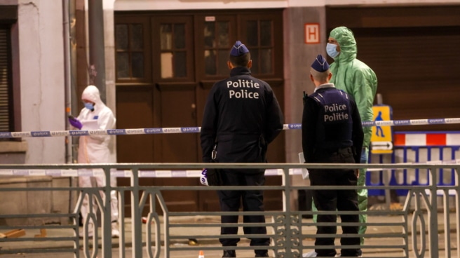 Agentes de policía y forenses belgas trabajan detrás de un cordón en el lugar de un tiroteo en Bruselas, Bélgica