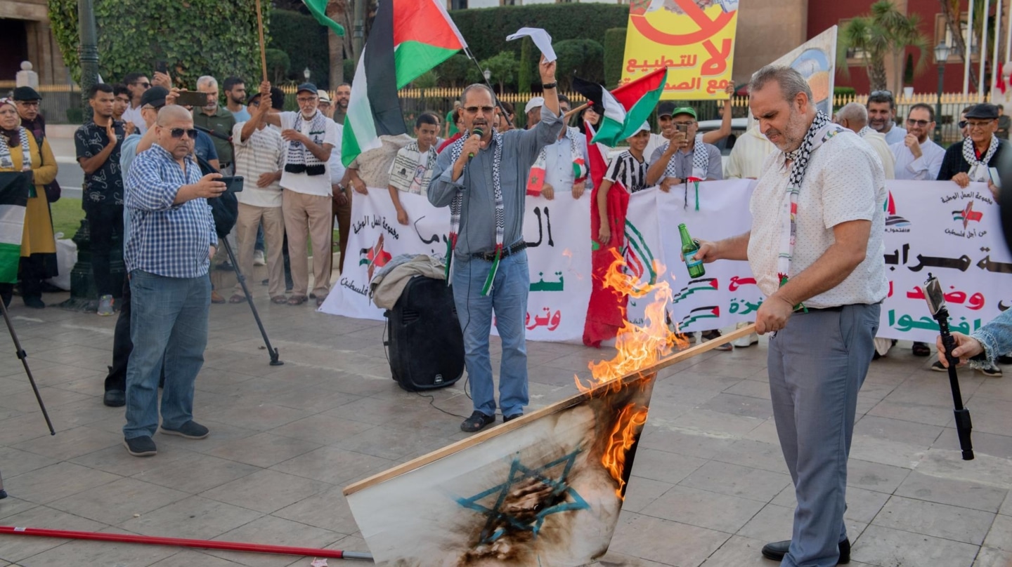 Un hombre quema una bandera israelí en una protesta en solidaridad con Palestina en Rabat.