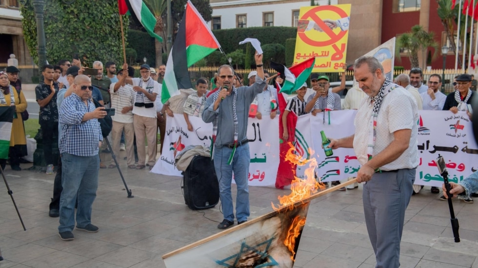 Un hombre quema una bandera israelí en una protesta en solidaridad con Palestina en Rabat.