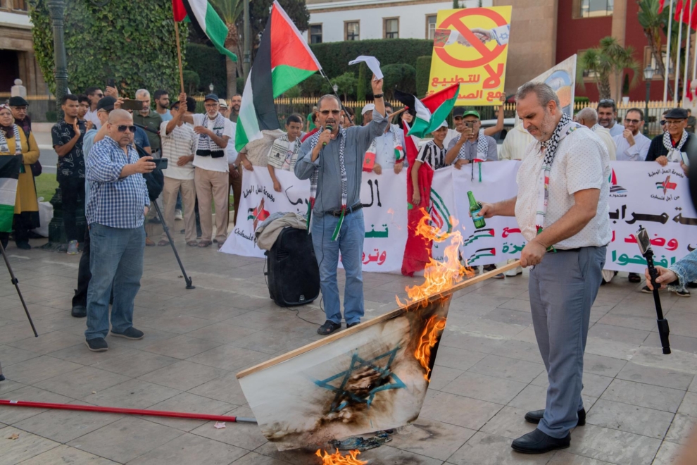 Un hombre quema una bandera israelí en una protesta en solidaridad con Palestina en Rabat.