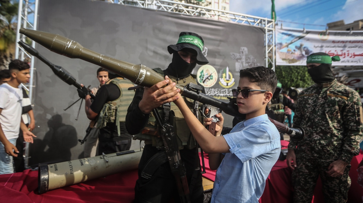 Un miembro del ala enseña a un niño un lanzagranadas en una exhibición en Gaza.