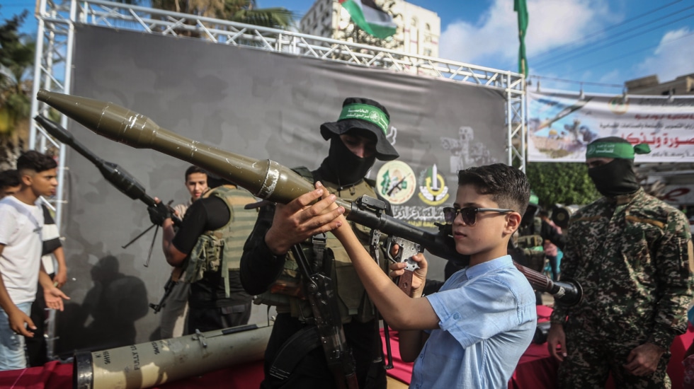 Un miembro del ala enseña a un niño un lanzagranadas en una exhibición en Gaza.