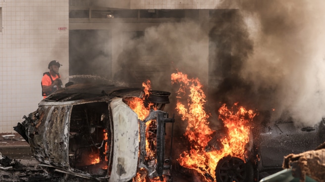 Varios vecinos de Ashkelon intentan apagar el fuego de un vehículo tras el ataque de Hamás.