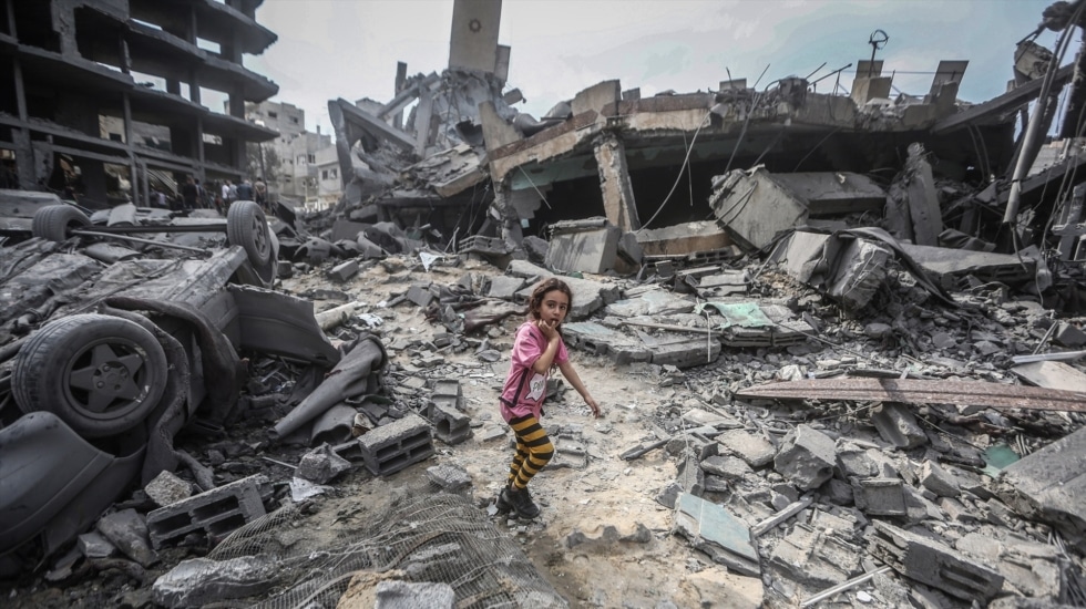 Una niña camina sobre las ruinas de un edificio destruido.