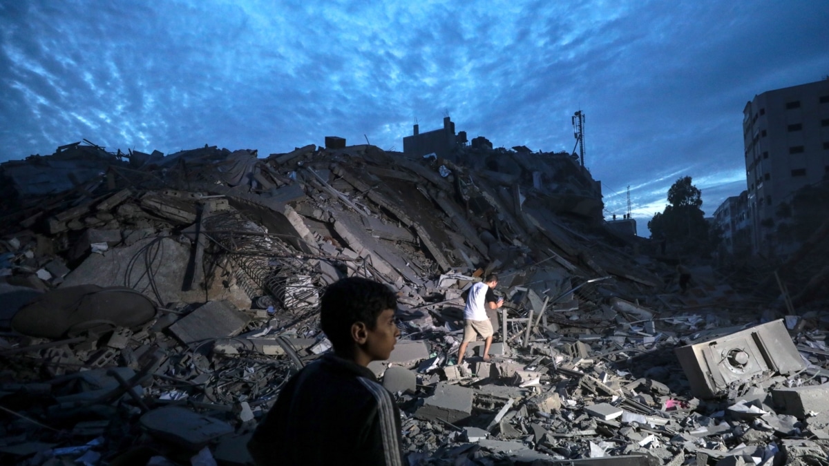 Menores inspeccionan los alrededores destruidos de la Torre Palestina después de que aviones de combate israelíes la atacaran en la ciudad de Gaza
