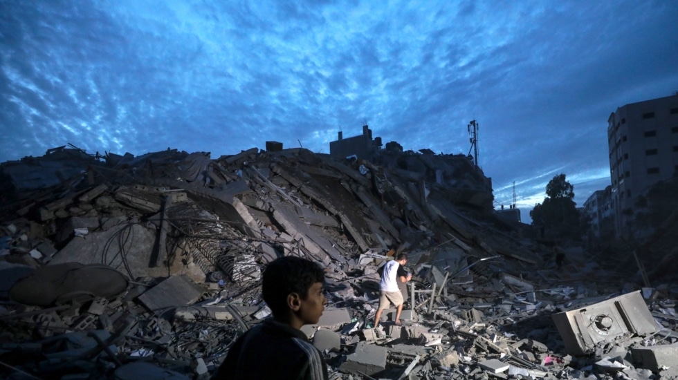 Menores inspeccionan los alrededores destruidos de la Torre Palestina después de que aviones de combate israelíes la atacaran en la ciudad de Gaza