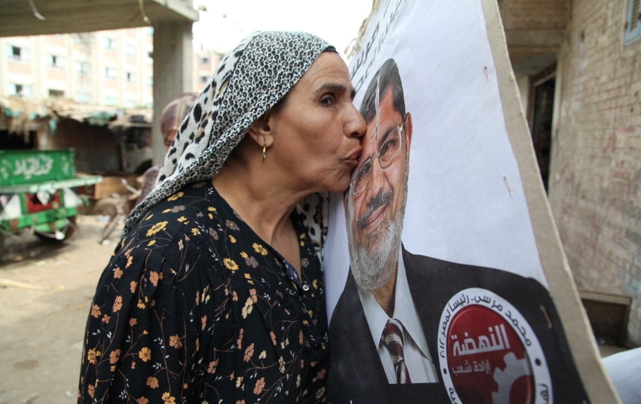 Una vecina del ex fallecido presidente egipcio Mohamed Mursi, dirigente de los Hermanos Musulmanes, besa un cartel de las presidenciales de 2013.