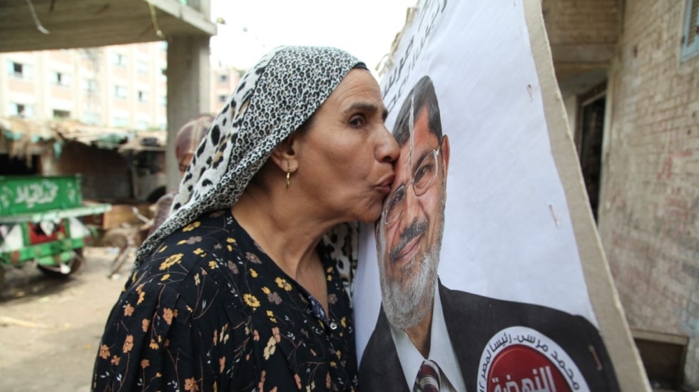 Una vecina del ex fallecido presidente egipcio Mohamed Mursi, dirigente de los Hermanos Musulmanes, besa un cartel de las presidenciales de 2013.