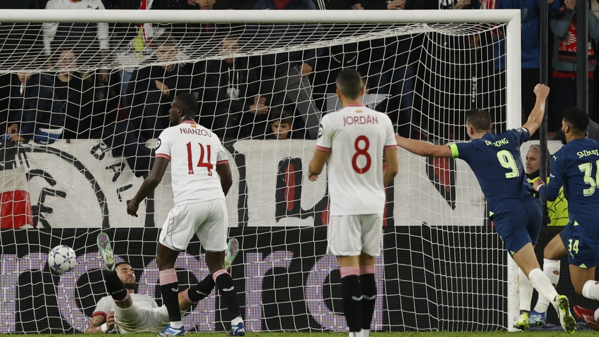 El defensa del Sevilla Nemanja Gudelj (i) en el suelo tras marcar en propia puerta el segundo gol del PSV al Sevilla en el Estadio Ramón Sánchez-Pizjúan