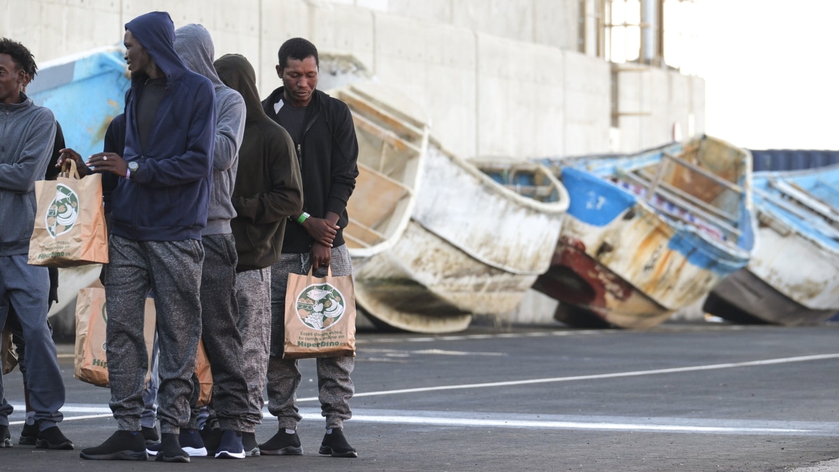 imagen de personas migrantes llegadas este lunes al puerto de Arinaga (Gran Canaria) con unos cayucos de fondo (Efe).