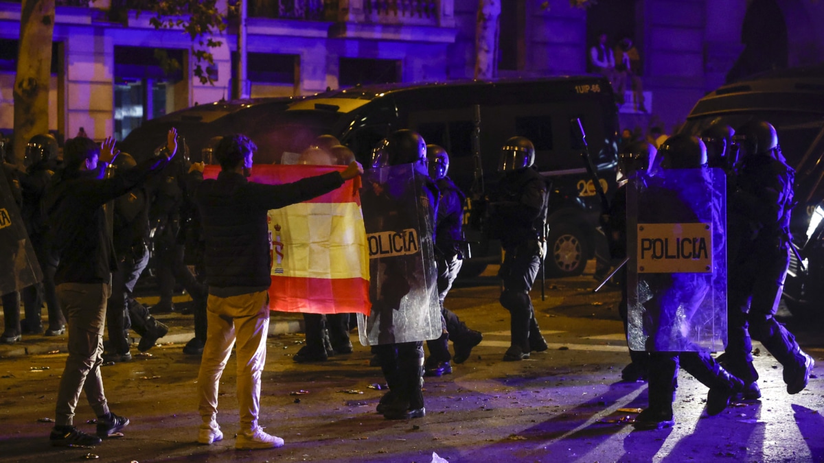 Una persona enseña una bandera de España a la policía durante una nueva manifestación convocada contra la amnistía este martes, frente a la sede del PSOE en Ferraz, Madrid (Efe).