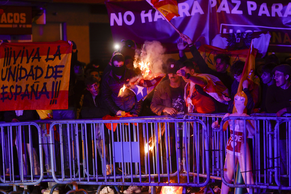Un grupo de personas quema una estelada catalana durante una concentración contra la Amnistía y la investidura tras el debate de investidura de Pedro Sánchez este miércoles, en la calle Ferraz, lugar de la sede central del PSOE en Madrid. 