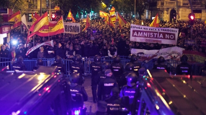 Decenas de personas con banderas y pancartas durante una concentración en contra de la amnistía, frente a la sede del PSOE en la calle Ferraz