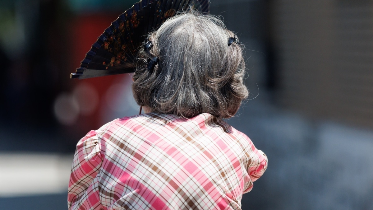 Una mujer mayor se protege del sol con un abanico en Madrid.