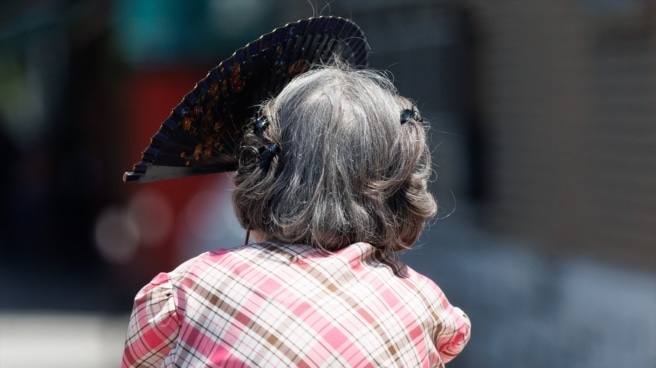 Una mujer mayor se protege del sol con un abanico en Madrid.