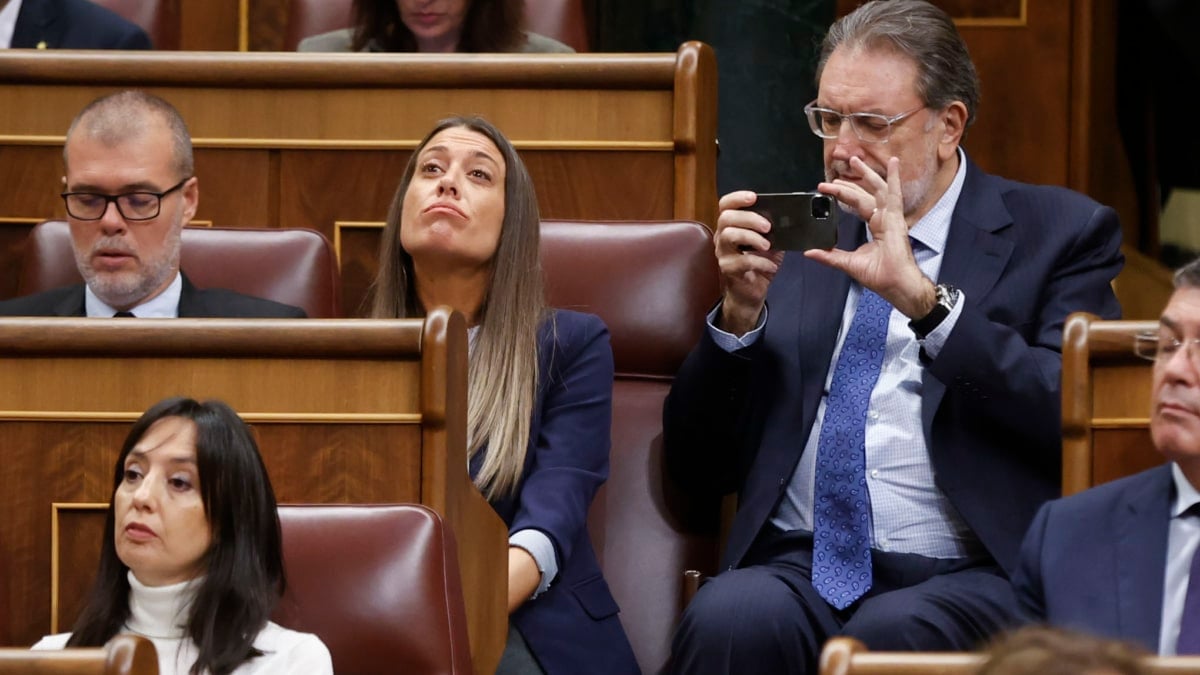 El senador de Junts de Catalunya Josep LLuis Cleires (d) toma imágenes con su teléfono mientras asiste junto a los diputados de su formación Míriam Nogueras y Josep María Cruset (i) al primer día deldebate de investidura del líder del PSOE, Pedro Sánchez