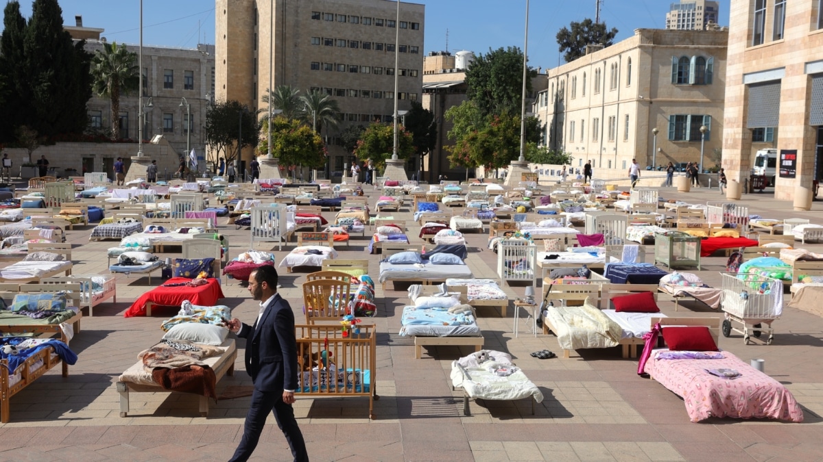Un hombre pasa junto a 230 camas vacías que representan los rehenes retenidos por Hamas en GazaE