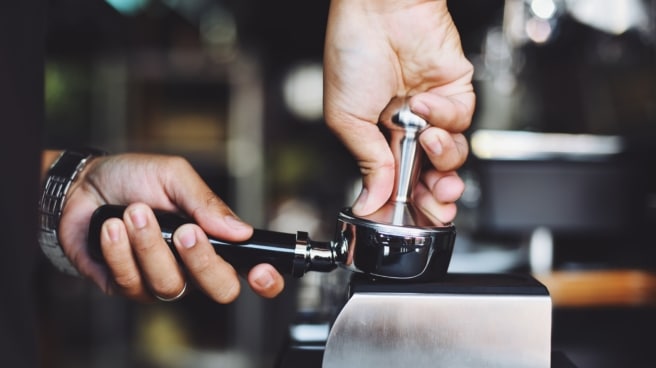 Un camarero retira los posos del café Un camarero retira los posos del café